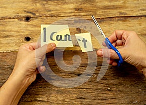 Woman hands using scissors to remove letter T from written text I can`t do it to read I can