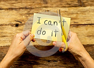 Woman hands using scissors to remove letter T from written text I can`t do it to read I can