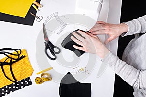 Woman hands using a sewing machine to sew a black face mask during the coronavirus pandemia.