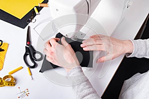 Woman hands using a sewing machine to sew a black face mask during the coronavirus pandemia. photo