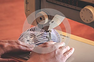 Woman hands using the sewing machine to sew a colorful face medical mask during the coronavirus pandemic. Homemade DIY