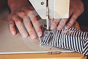 Woman hands using the sewing machine to sew a colorful face medical mask during the coronavirus pandemic. Homemade DIY