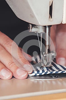 Woman hands using the sewing machine to sew a colorful face medical mask during the coronavirus pandemic. Homemade DIY