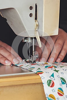 Woman hands using the sewing machine to sew a colorful face medical mask during the coronavirus pandemic. Homemade DIY protective