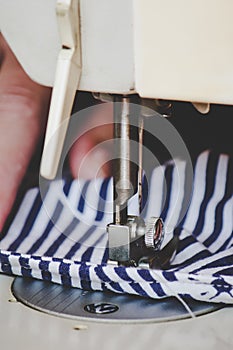 Woman hands using the sewing machine to sew a colorful face medical mask during the coronavirus pandemic. Homemade DIY protective