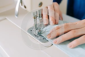 Woman hands using the sewing machine to sew the face home made diy medical mask during the coronavirus pandemia.