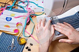 Woman hands using the sewing machine to sew the face mask during the coronavirus pandemia. Domestic sewing due to the shortage of