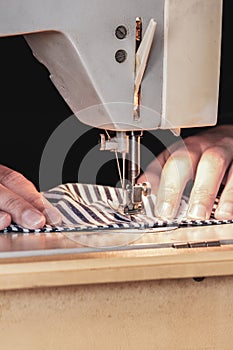 Woman hands using the sewing machine to sew the face medical mask during the coronavirus pandemic. Homemade DIY protective mask