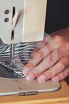 Woman hands using the sewing machine to sew the face medical mask during the coronavirus pandemic. Homemade protective