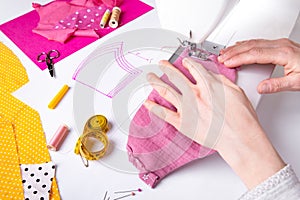 Woman hands using a sewing machine to sew a pink ladies face mask during the coronavirus pandemia photo