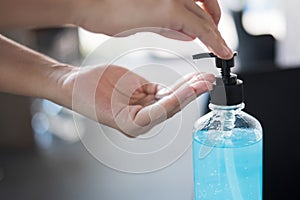 Woman hands using wash hand sanitizer gel dispenser, against Novel coronavirus or Corona Virus Disease Covid-19 at public train