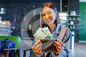 Woman hands with wallet and euro banknote money in cafe