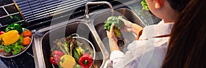 Woman hands washing Vegetables for Preparation of vegan salad on the worktop near to sink in a modern kitchen, Homemade healthy