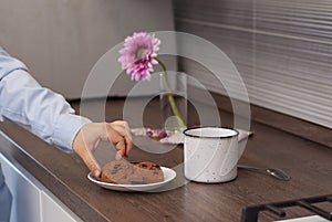 Woman hands with white tea cup and choccolate cookies. Selective focus. Kitchen teatime. Time rest and home. Gray walls