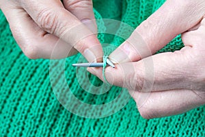 Woman hands who knits a green sweater