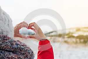 Woman hands in winter Heart shaped symbol of feelings and lifestyle concept with nature sunset light in the background.