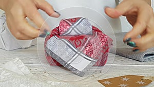 Woman hands wrap present in cloth. Furoshiki eco-friendly gift wrapping
