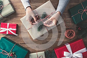 Woman hands wrapping christmas gifts on a wooden table