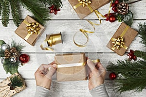 Woman hands wrapping gift box on wooden background