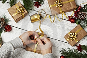 Woman hands wrapping gift box on wooden background