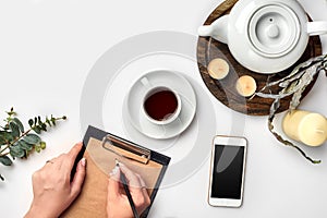 A woman hands writing on empty book note, diary, spread mockup, top view, studio. Cup of coffee break.