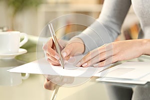 Woman hands writing a letter on a desk at home