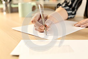 Woman hands writing letter sitting on a desk