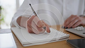 Woman hands writing in notebook wooden table closeup. Businesswoman making notes
