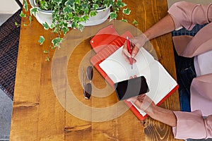 Woman hands writing on an orange agenda and holding cell phone