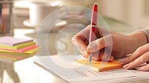 Woman hands writing on stiky note on a desk