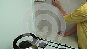 Woman hands with yellow sponge clean ceramic tile in kitchen close-up.