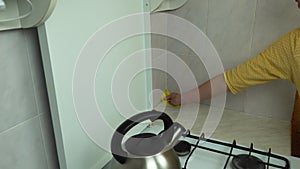 Woman hands with yellow sponge clean ceramic tile in kitchen close-up.