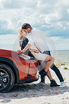 Woman and handsome man kissing on car outside