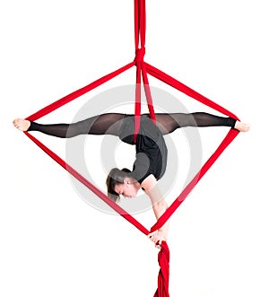 Woman hanging in aerial silks, isolated on white