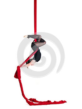 Woman hanging in aerial silks, isolated on white