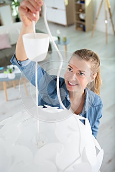 woman hanging ceiling light in home