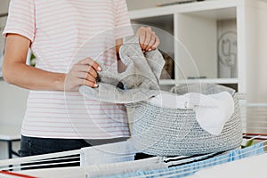 Woman hanging clean wet clothes laundry on drying rack at home laundry room