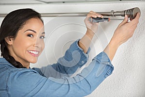 woman hanging curtains curtains at home