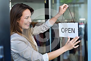 Woman hanging open sign on door