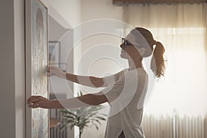 Woman hanging a painting at home