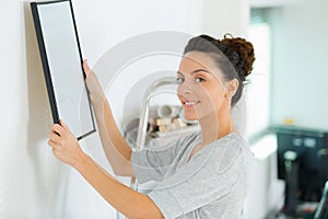 Woman hanging picture on wall