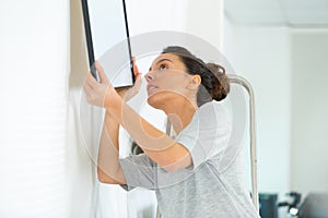 Woman hanging picture on wall