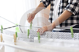 Woman hanging wet clothes with clothespins