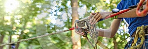 Woman hangs a carabiner on a rope in a forest adventure park. Using climbing equipment: carabiner, belt, rope. Banner