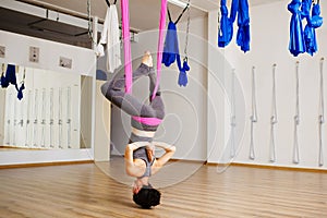 Woman hangs upside down doing aero anti gravity yoga exercises