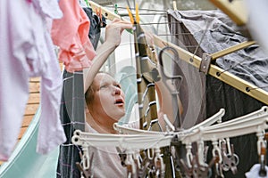 A woman hangs washed wet clothes after washing on a dryer in the yard