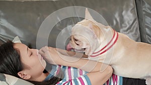 Woman is happily fun playing and teasing dog French Bulldog.