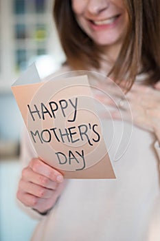 Woman happy about being a mother, holding a mother\'s day greeting card