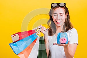 Woman happy hold colorful shopping bags and Piggybank Saving money