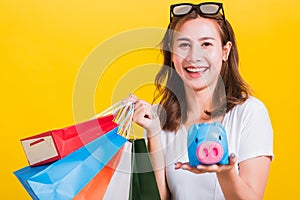 Woman happy hold colorful shopping bags and Piggybank Saving money